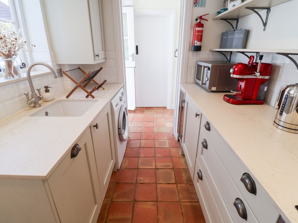 A kitchen with a washing machine and coffee machine at Victoria Cottage (4 East Green) Southwold