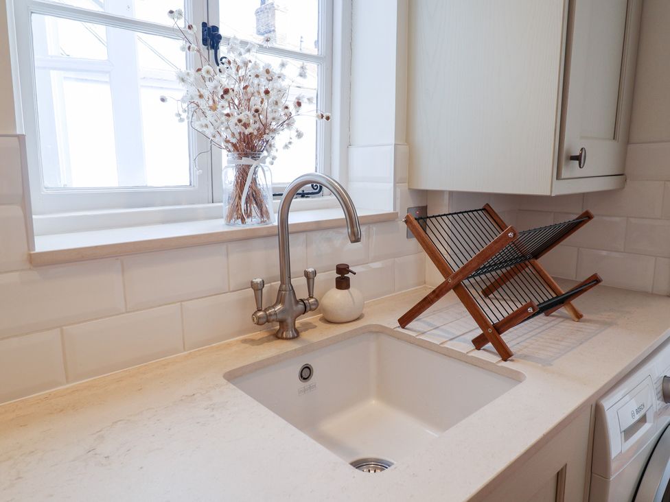 A kitchen sink with a drying rack and a flower vase at Victoria Cottage (4 East Green) Southwold