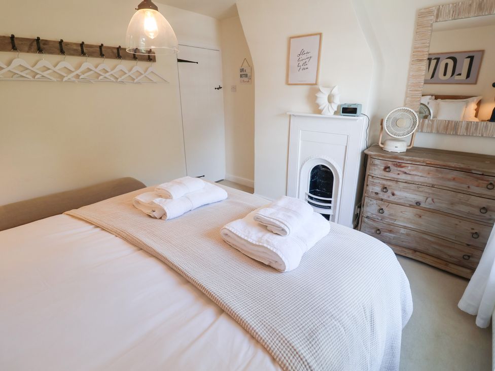 A bedroom with a bed and towels at Victoria Cottage (4 East Green) Southwold