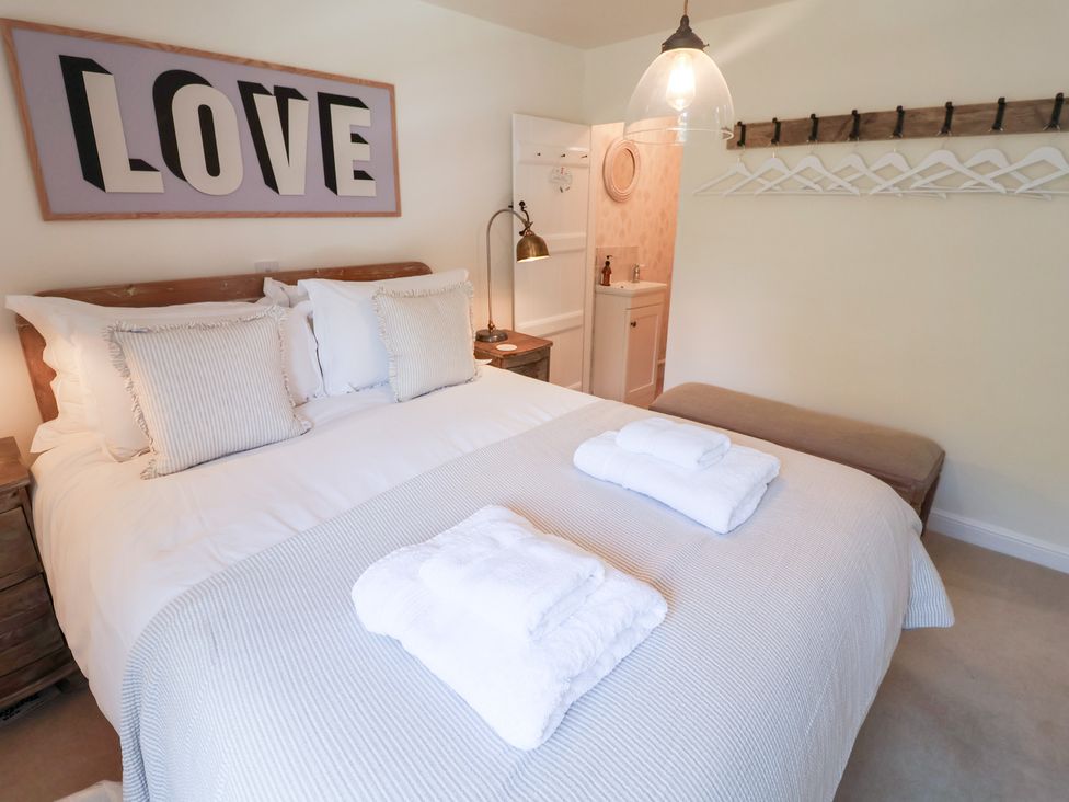 A bedroom with a bed and towels at Victoria Cottage (4 East Green) Southwold