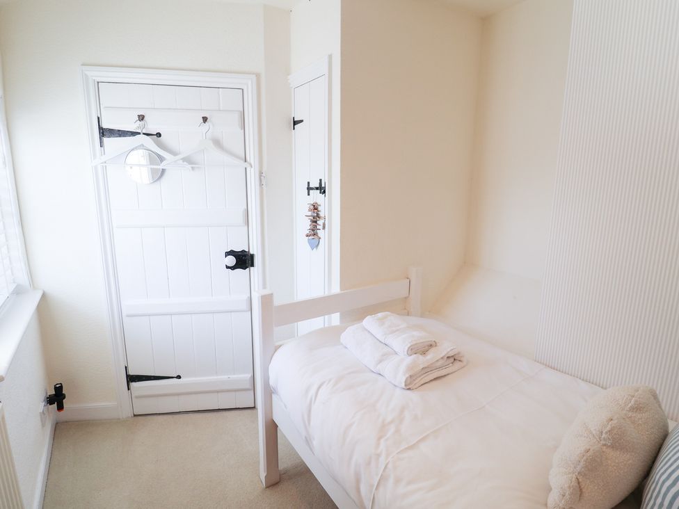 A bedroom with a bed and towels at Victoria Cottage (4 East Green) Southwold