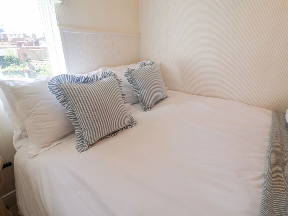 A bed with pillows and cushions at Victoria Cottage (4 East Green) Southwold