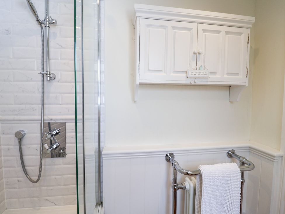 A bathroom with a shower and storage cabinet at Victoria Cottage (4 East Green) Southwold