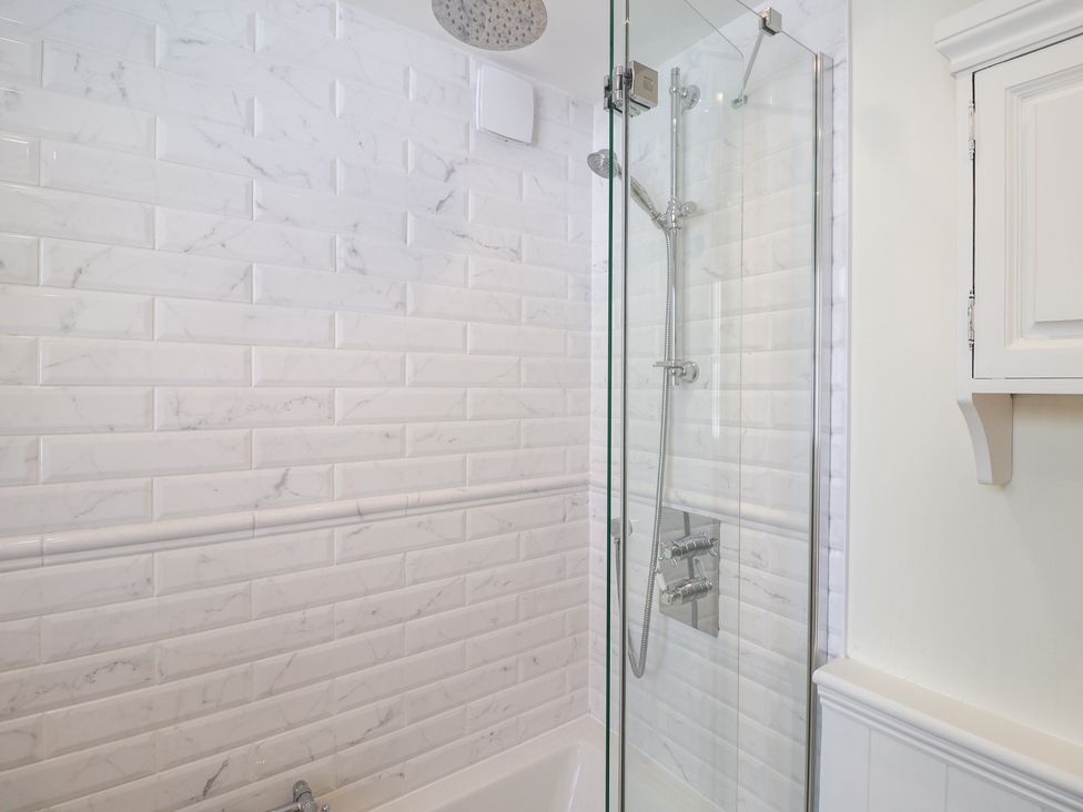 A bathroom with a glass shower and bathtub at Victoria Cottage (4 East Green) Southwold