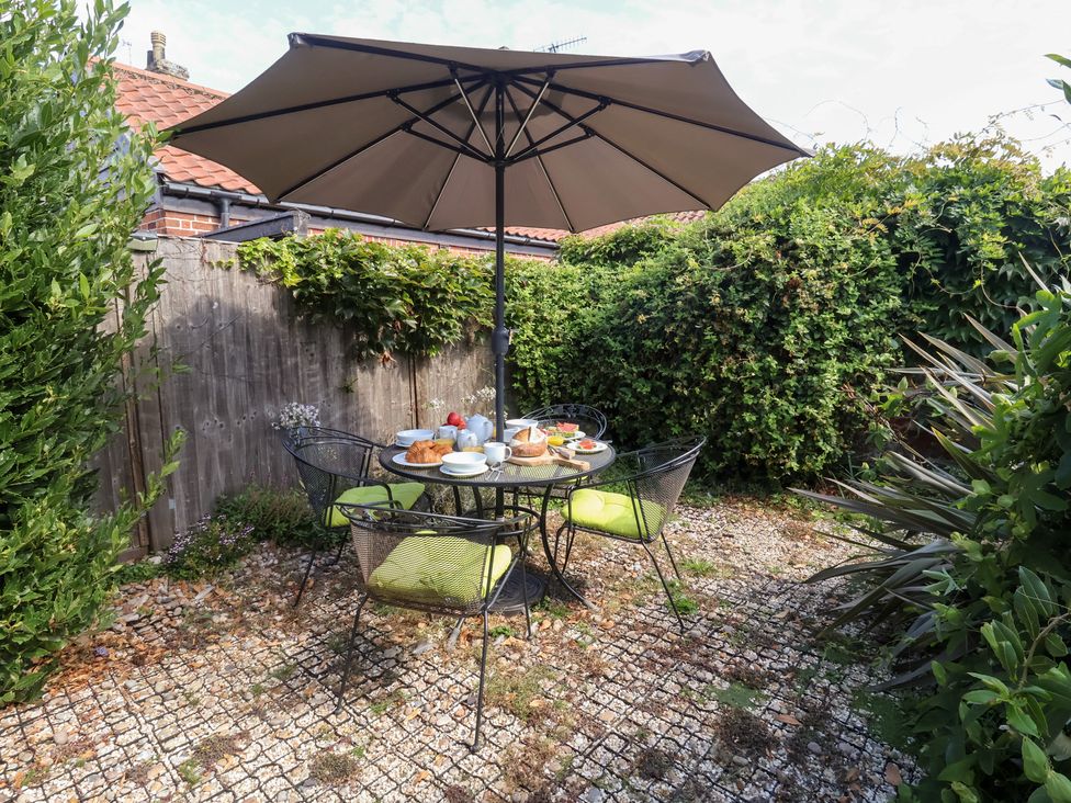 A table with food and an umbrella in a garden at Victoria Cottage (4 East Green) in Southwold