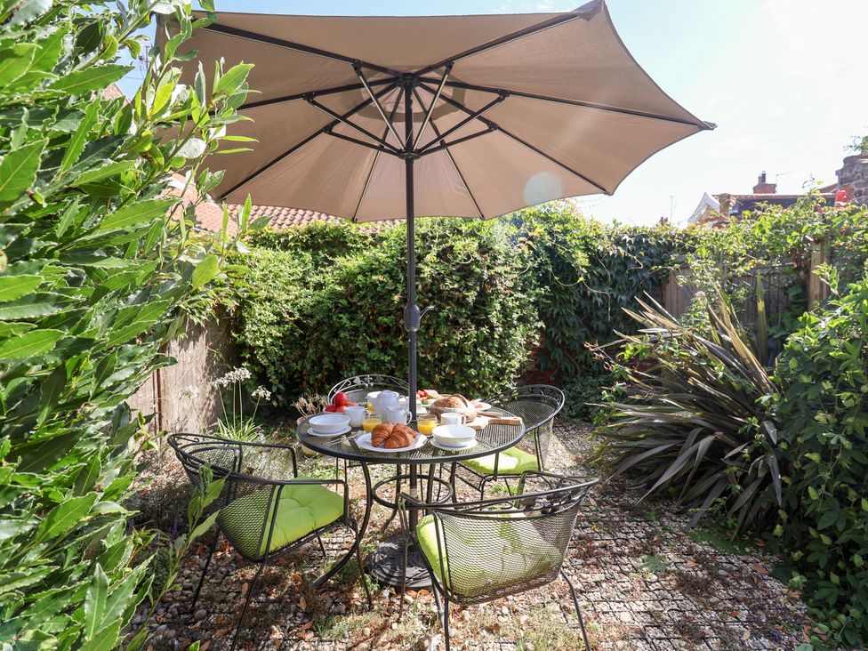 A garden with a table and chairs under an umbrella at Victoria Cottage (4 East Green) Southwold