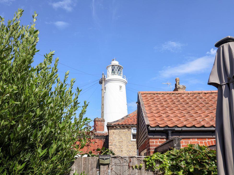 A lighthouse and houses visible from a garden at Victoria Cottage (4 East Green) Southwold