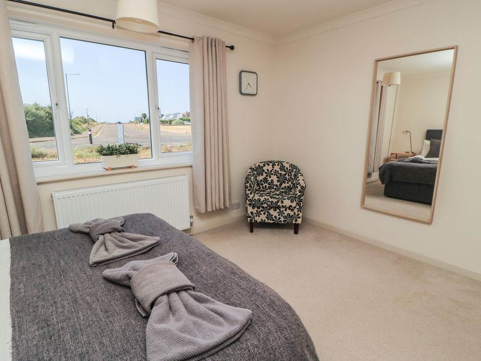 A bedroom with a bed and chair at Bayview Cottage Southbourne