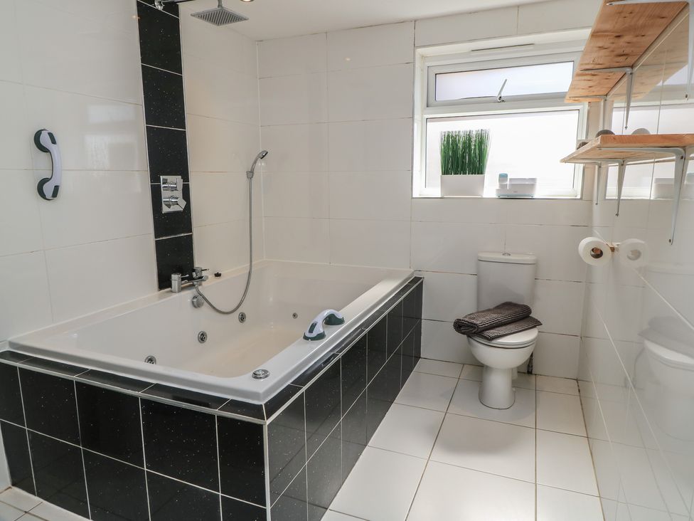 A bathroom featuring a bathtub, toilet, and shelves at Bayview Cottage Southbourne