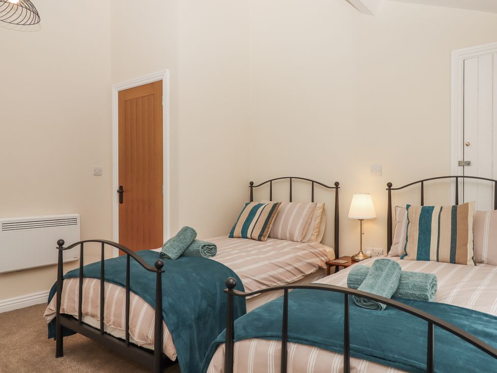 A bedroom with two beds and a bedside table at Aunty Junes Cottage Okehampton