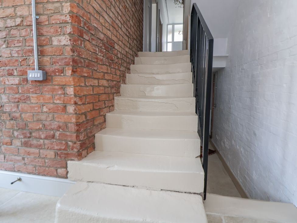 A staircase with a brick wall and light switch at 33 Lorne Street Chester