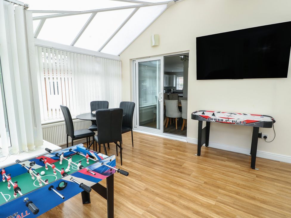 A conservatory with a foosball table and air hockey table at 9 Beckett Close in Colwyn Bay