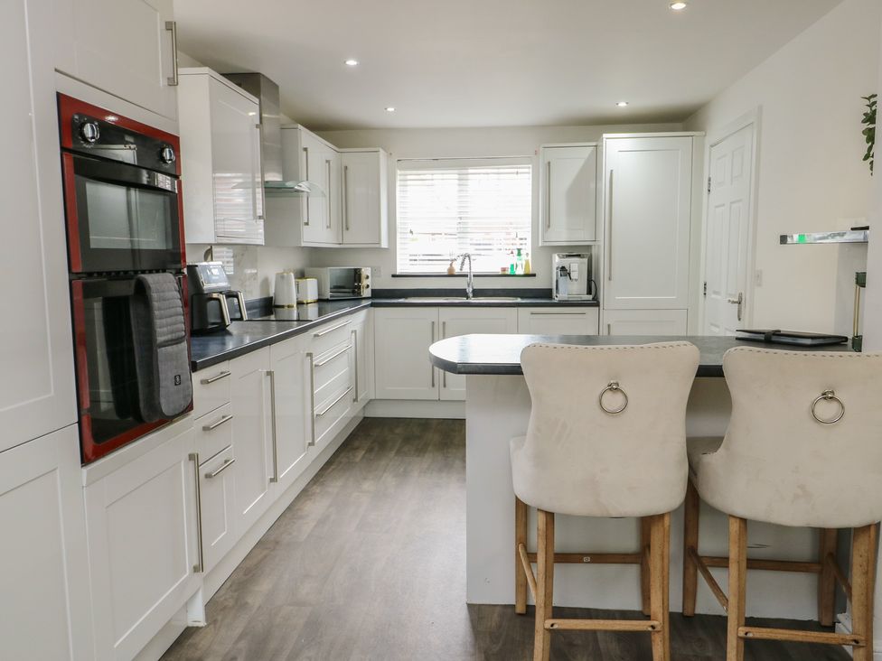 A kitchen with appliances and bar stools at 9 Beckett Close in Colwyn Bay