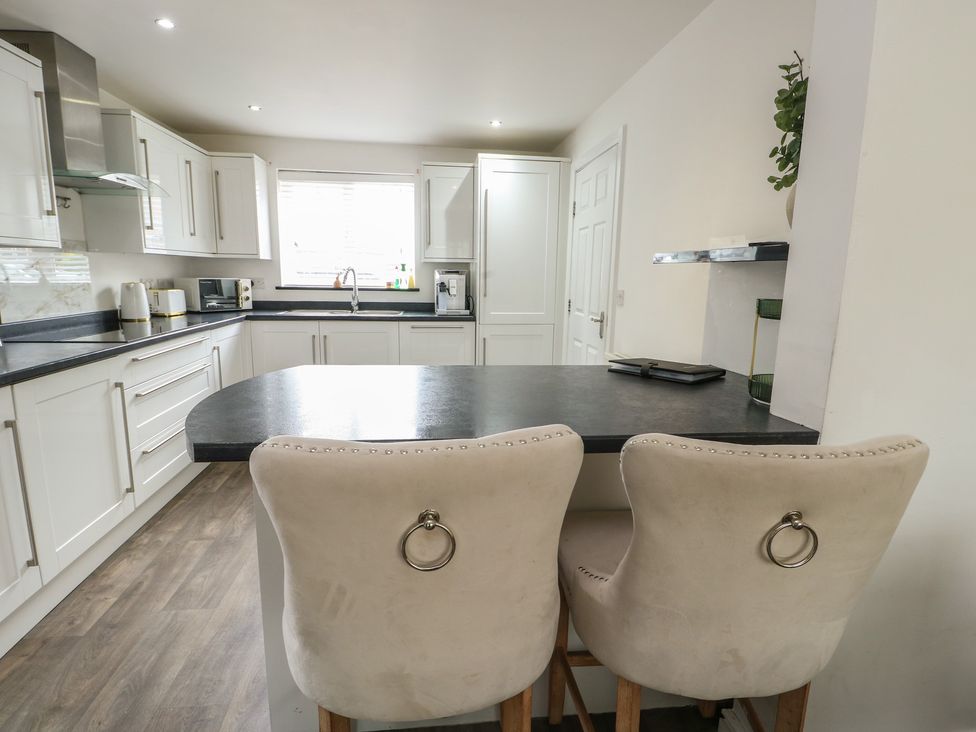 A kitchen with bar stools and a window at 9 Beckett Close in Colwyn Bay