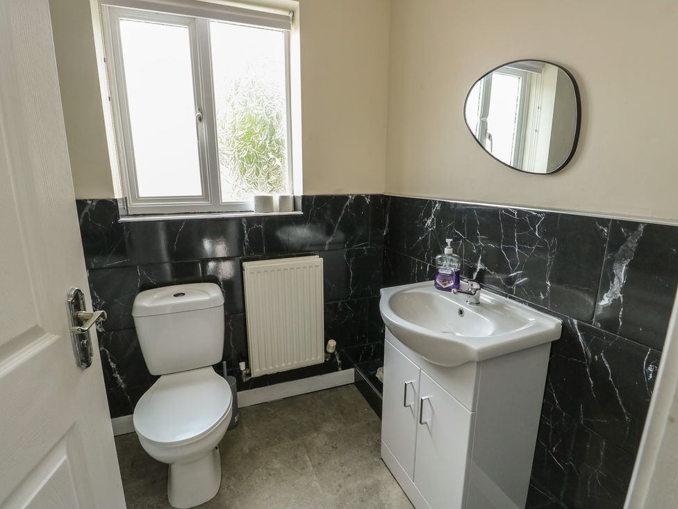 A bathroom with a toilet, sink, and window at 9 Beckett Close Colwyn Bay