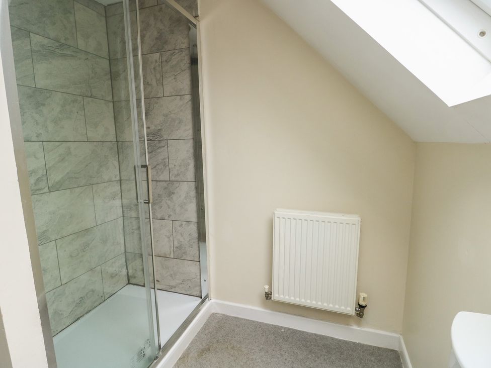 A bathroom with a shower and radiator at 9 Beckett Close in Colwyn Bay