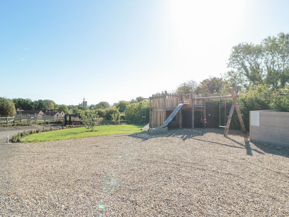 An outdoor playhouse with slide and swings at Hare's Hill in Thornton-Le-Dale