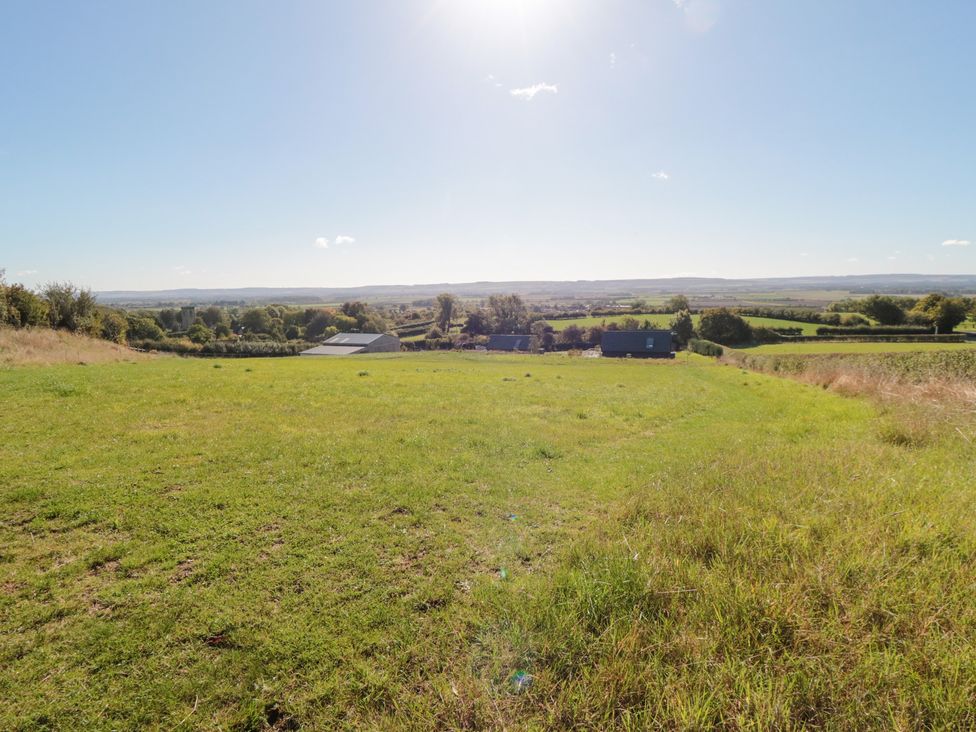 A grassy field with buildings in the background at Hare's Hill Thornton-Le-Dale