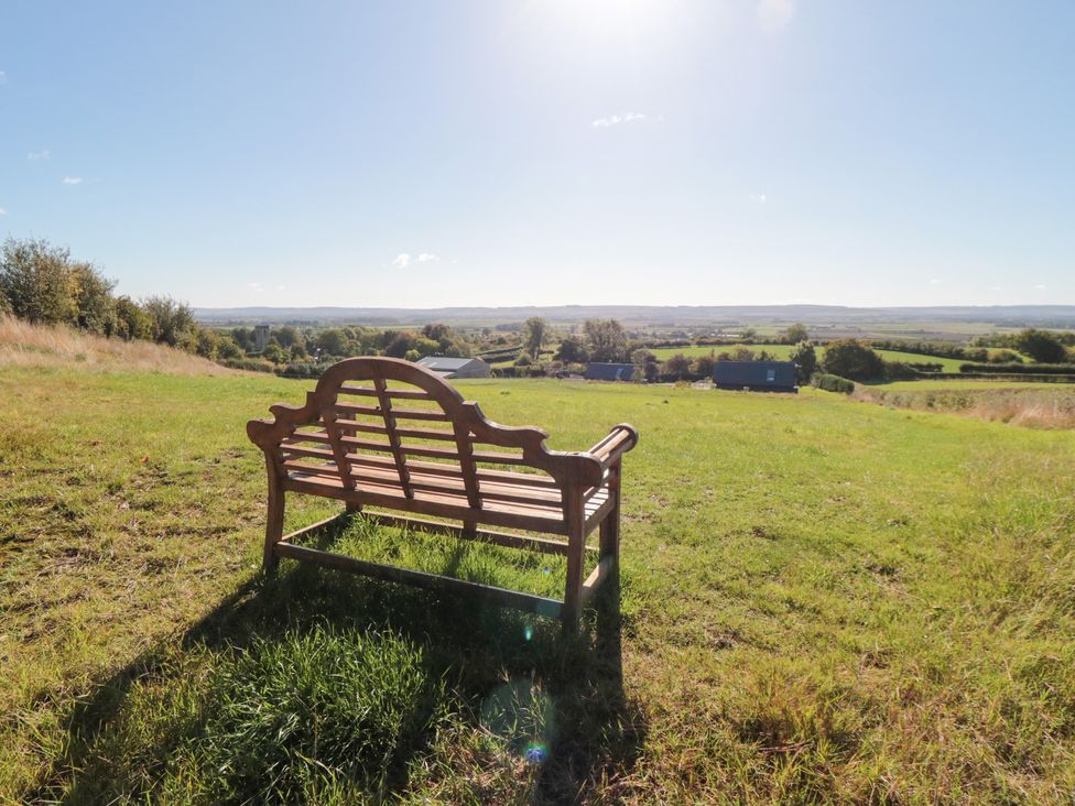A bench in a grassy area with fields in the distance at Hare's Hill in Thornton-Le-Dale