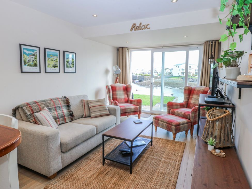 A living room with a sofa and armchairs overlooking a view at Oakley View Apartment in Porthmadog
