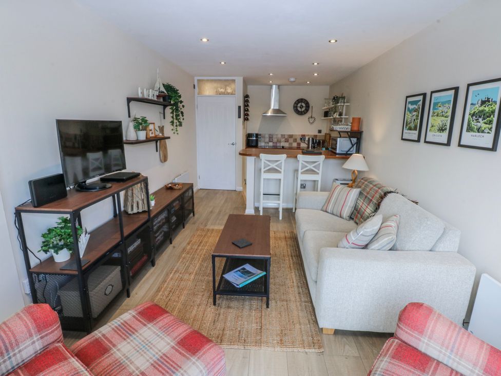 A living room with a television, sofa, and kitchenette at Oakley View Apartment in Porthmadog
