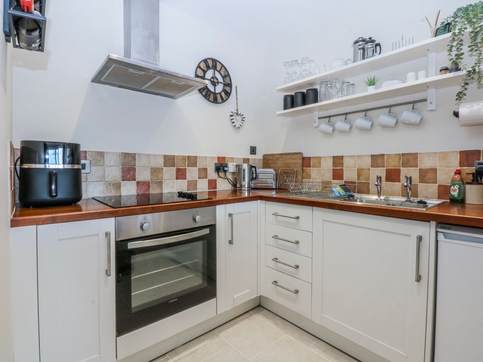 A kitchen with a countertop, oven, air fryer, and sink at Oakley View Apartment Porthmadog