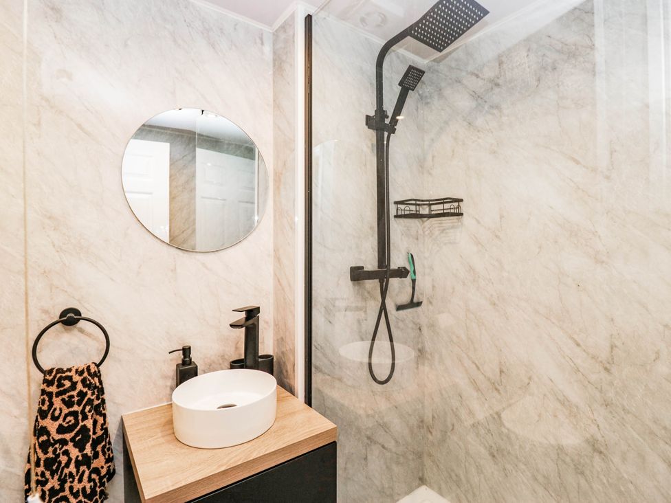 A bathroom with a shower, sink, and mirror at 2 Bakers Yard