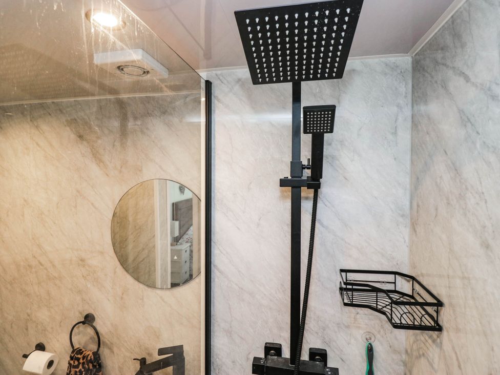 A bathroom with a shower and a mirror at 2 Bakers Yard