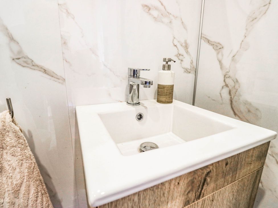 A sink with a faucet and soap dispenser in a bathroom at 2 Bakers Yard