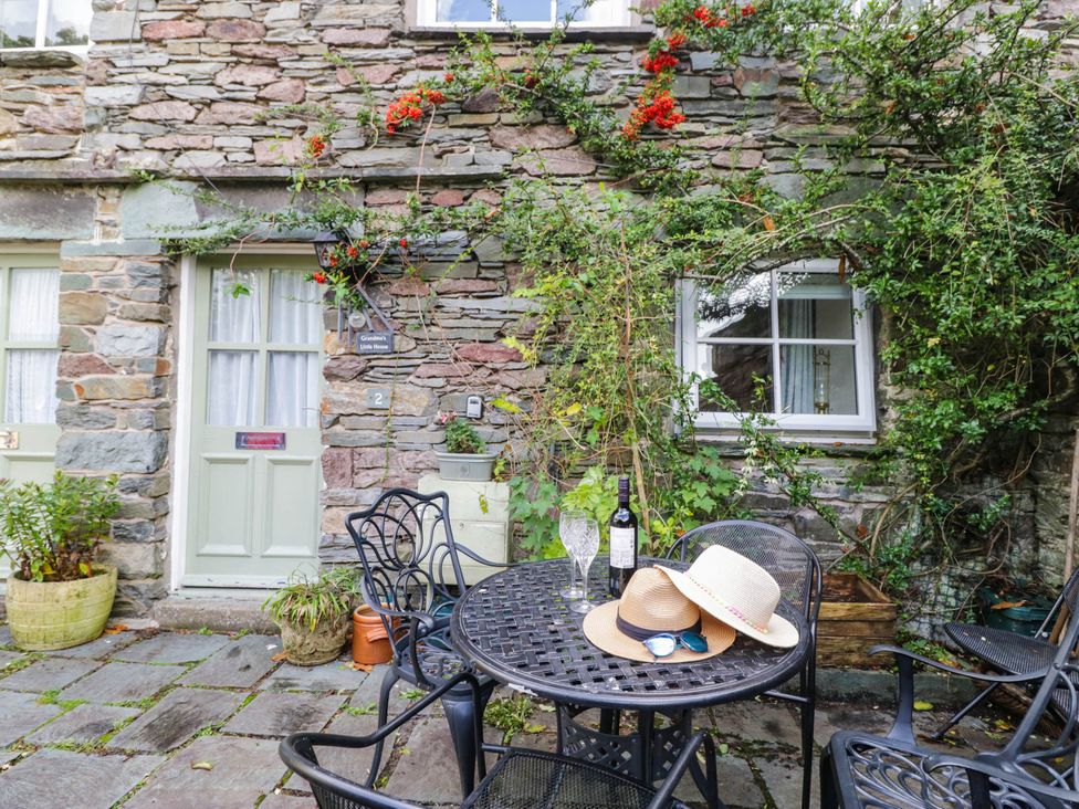 An outdoor area with a table and chairs near stone walls at 2 Bakers Yard