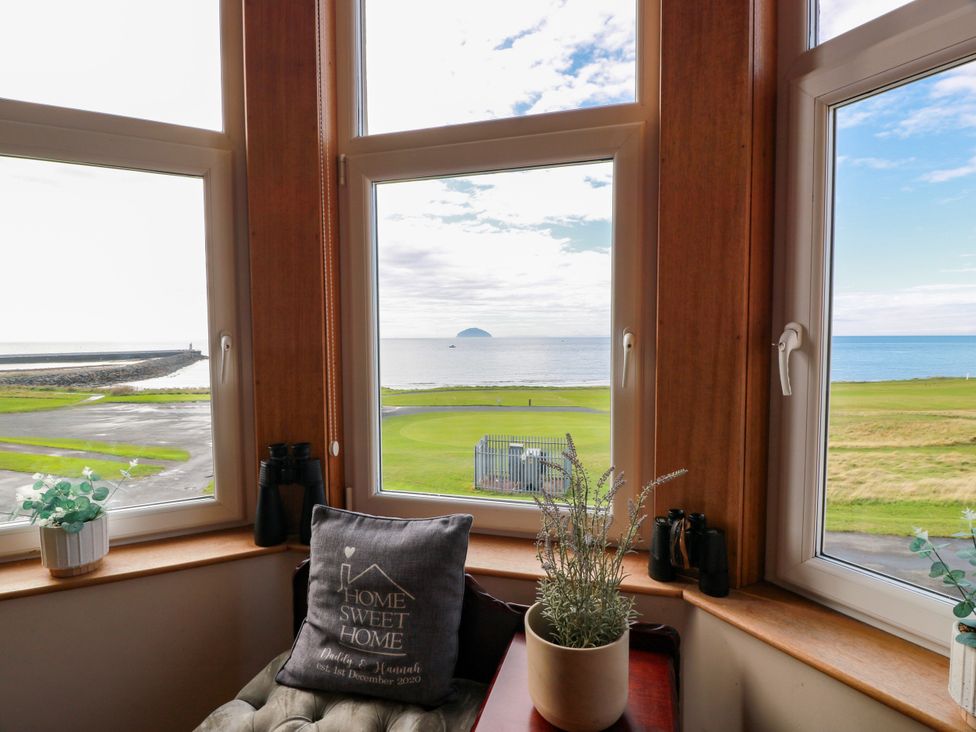 A living room with windows overlooking the ocean and golf course at Ailsa View in Girvan