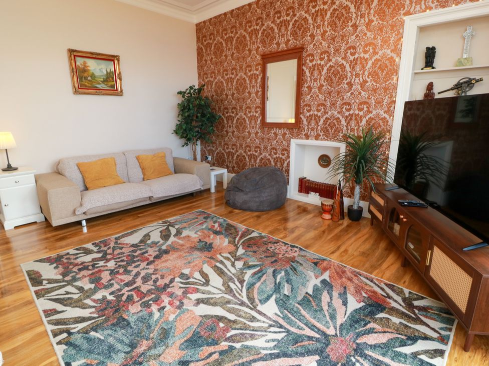 A living room with a sofa, rug, and television at Ailsa View in Girvan