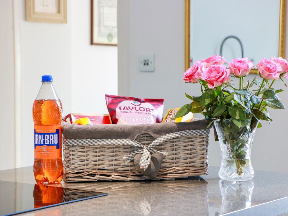 A kitchen with a bottle of drink and a basket on the counter at Ailsa View in Girvan
