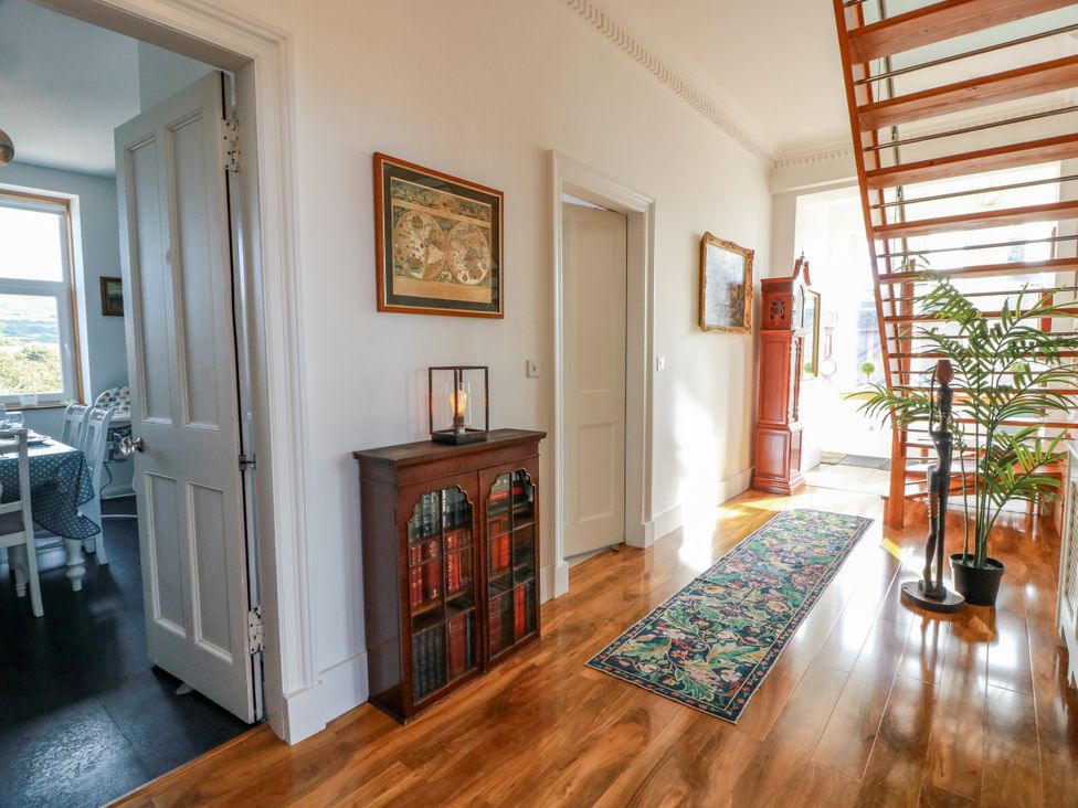 A hallway with a bookshelf, a plant, and a staircase at Ailsa View in Girvan