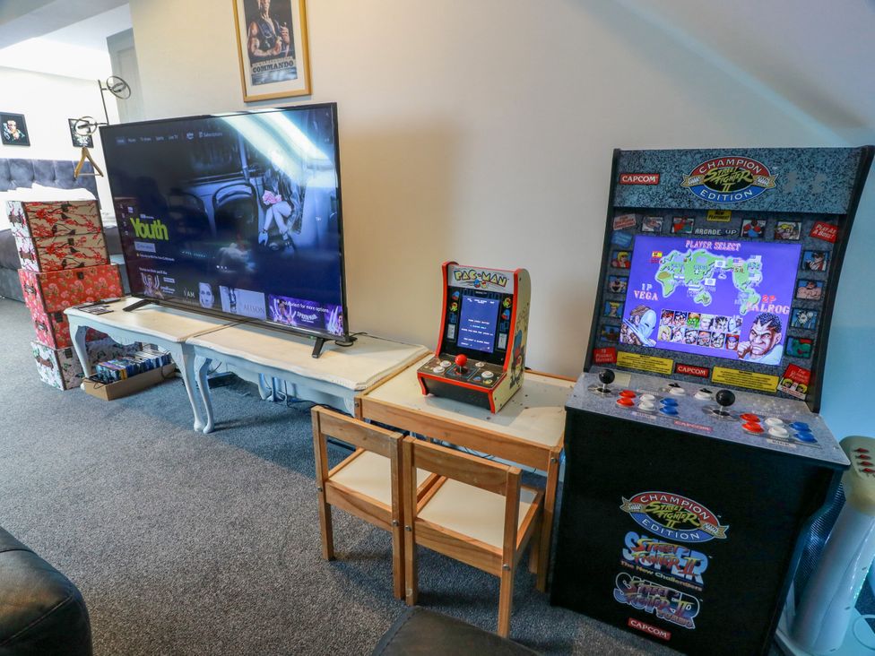 A living room with a television and arcade games at Ailsa View in Girvan