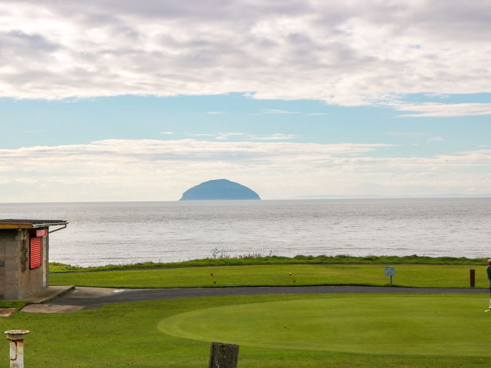 A golf course with ocean view and an island in the distance at Ailsa View in Girvan