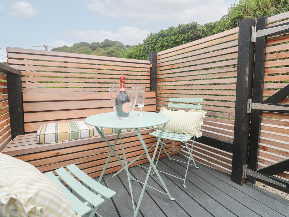 An outdoor seating area with a table, chairs, and a bottle of champagne at Mavericks Wave in St Agnes