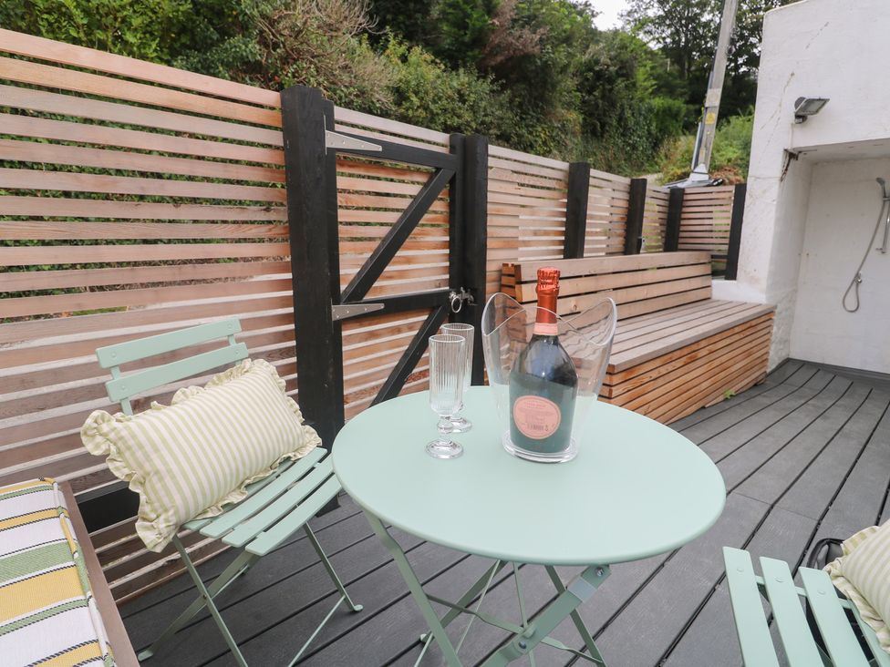 An outdoor area with a table, chairs, and a bottle of champagne at Mavericks Wave, St Agnes