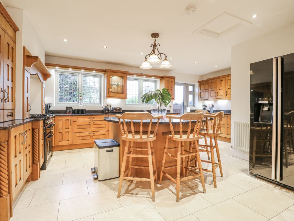 A kitchen with wooden cabinets and bar stools at Mellbreak in Ashby-De-La-Zouch