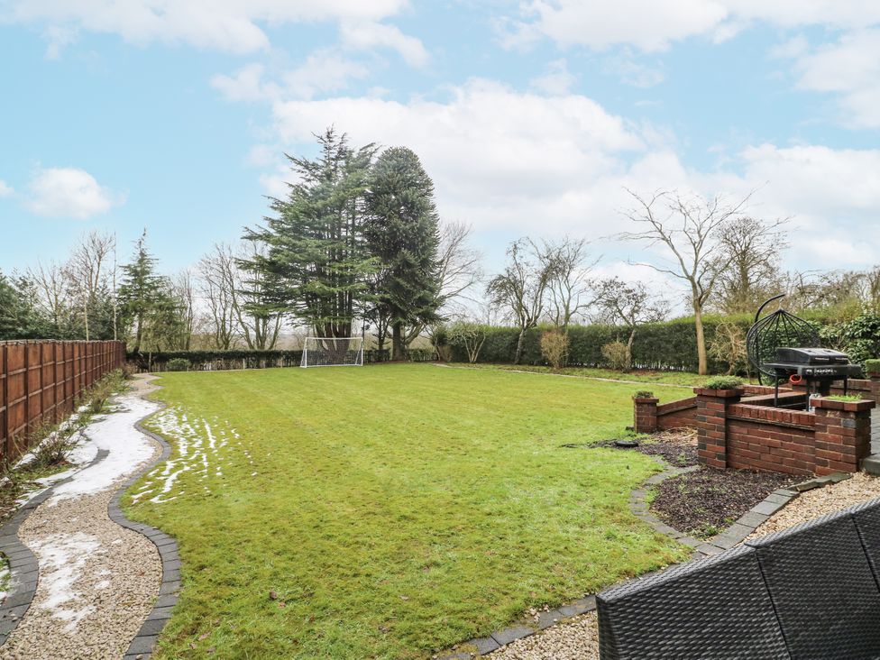 A garden with grass, trees, and a barbecue at Mellbreak in Ashby-De-La-Zouch