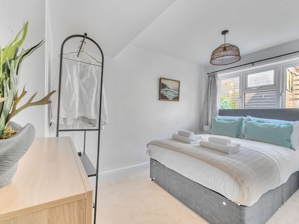 A bedroom with a bed and clothes rack at Palm House in Newquay