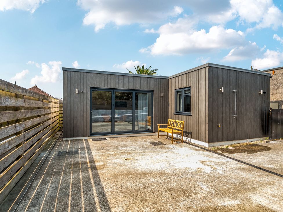A modern building with large windows and a yellow bench outside at Palm House in Newquay