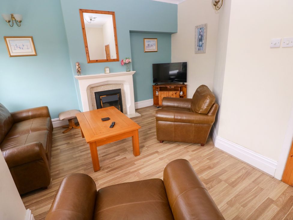 A living room with a coffee table and television at The Bungalow in Porthcawl