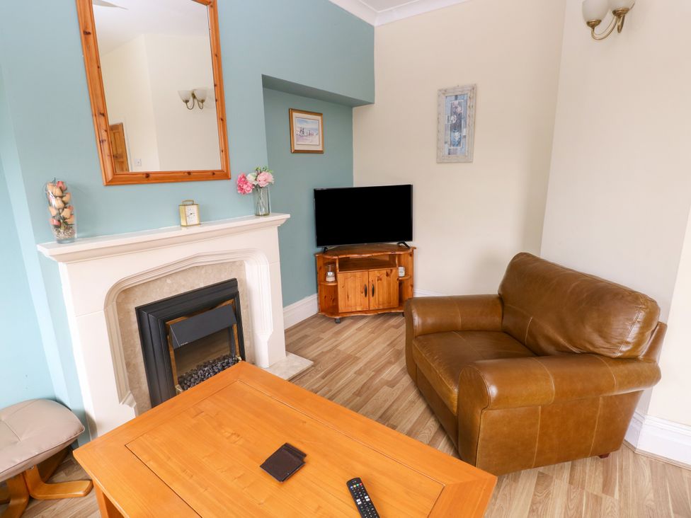 A living room with a fireplace and television at The Bungalow in Porthcawl