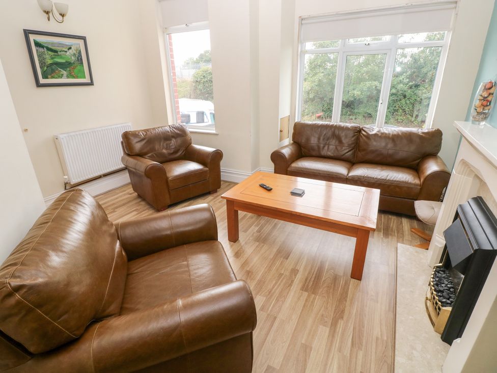 A living room with leather sofas and a coffee table at The Bungalow in Porthcawl