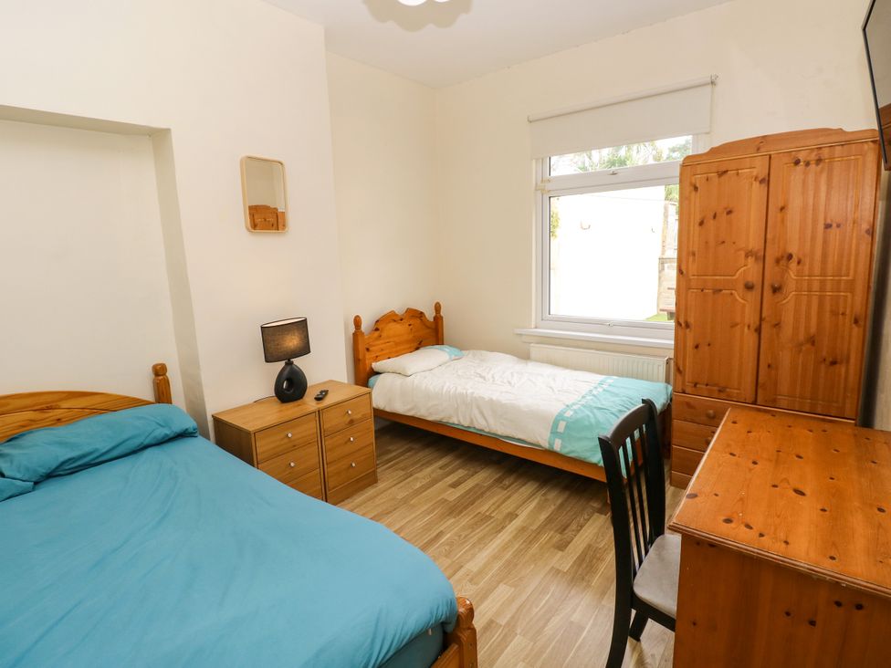 A bedroom with two beds and a desk at The Bungalow in Porthcawl