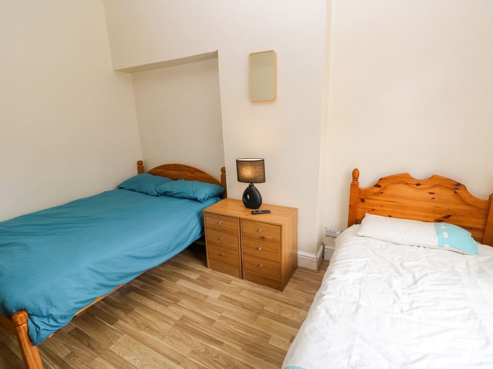 A bedroom with two beds and a bedside table at The Bungalow in Porthcawl