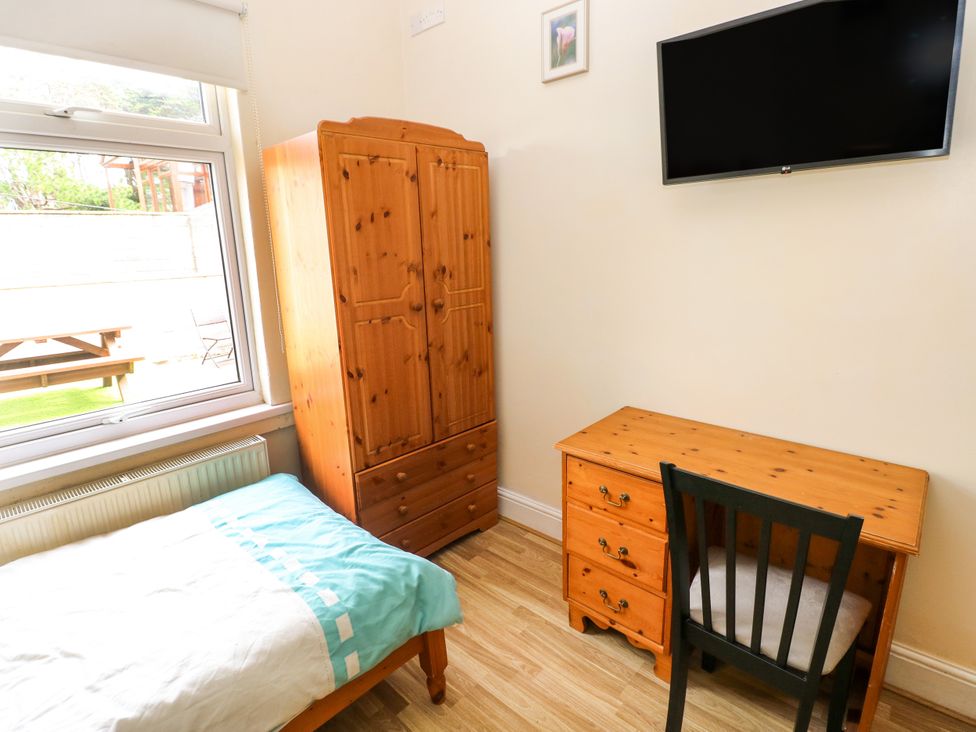 A bedroom with a bed, wardrobe, desk, and television at The Bungalow in Porthcawl