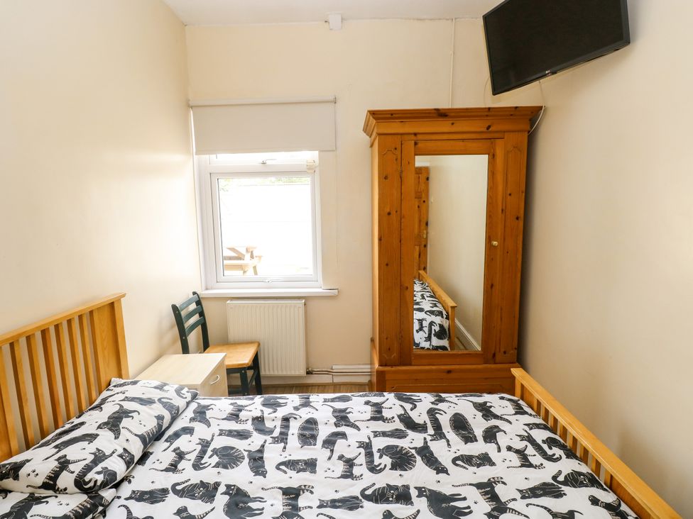 A bedroom with a bed, wardrobe, and table at The Bungalow in Porthcawl