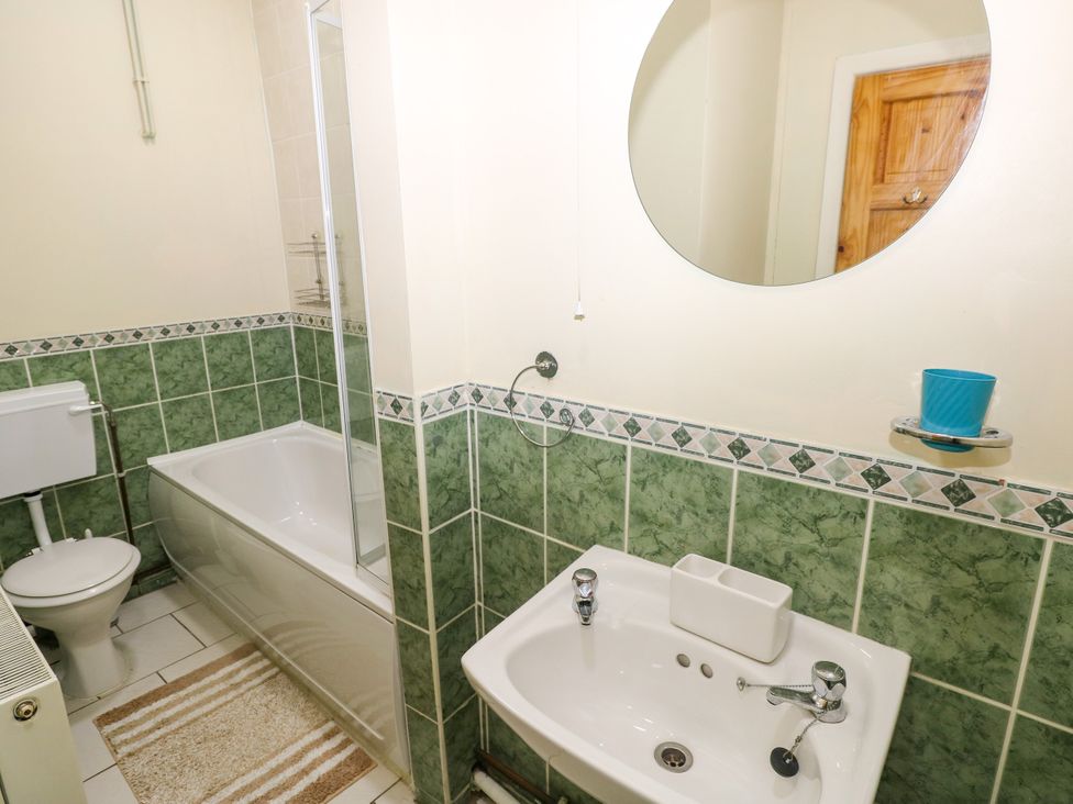 A bathroom with a bathtub, toilet, and sink at The Bungalow in Porthcawl